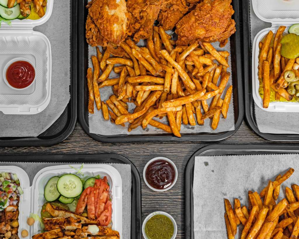 Overhead spread of fried chicken, fries, salad and sauces